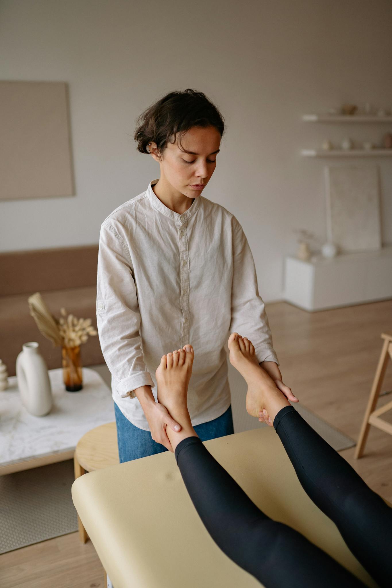 Therapist performing foot massage on woman indoors, promoting relaxation.